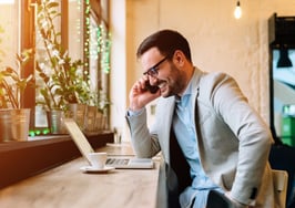 Man on phone looking at laptop